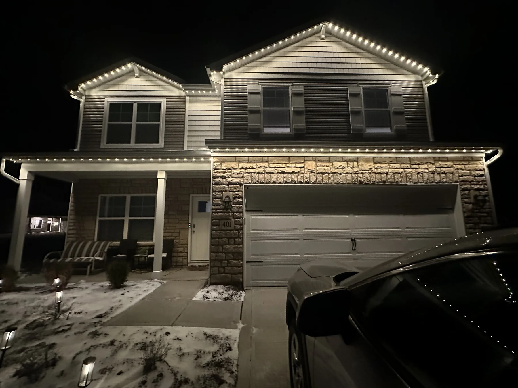Nighttime photo of a home with front placement, warm white lights spreading wide and washing the entire front face