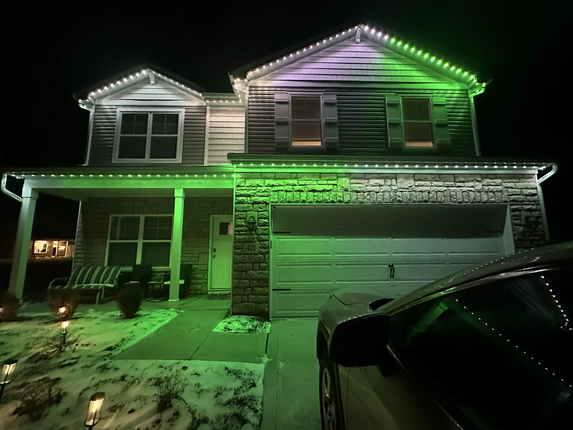 Two-story Columbus home at night with permanent Christmas lights washing the architecture in green and purple
