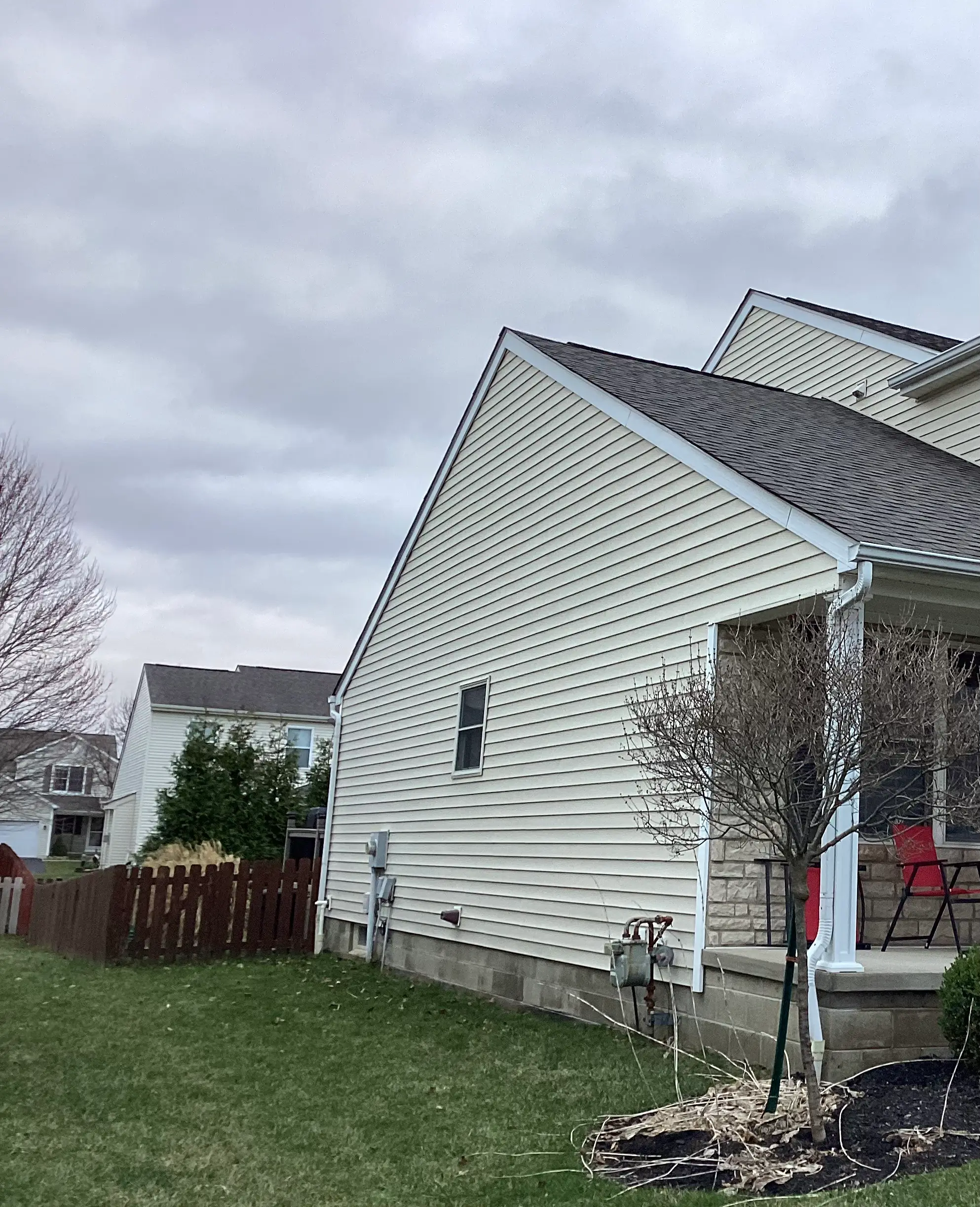 Daytime photo of another home where the entire gable end has no soffit, with siding running straight up to the roofline