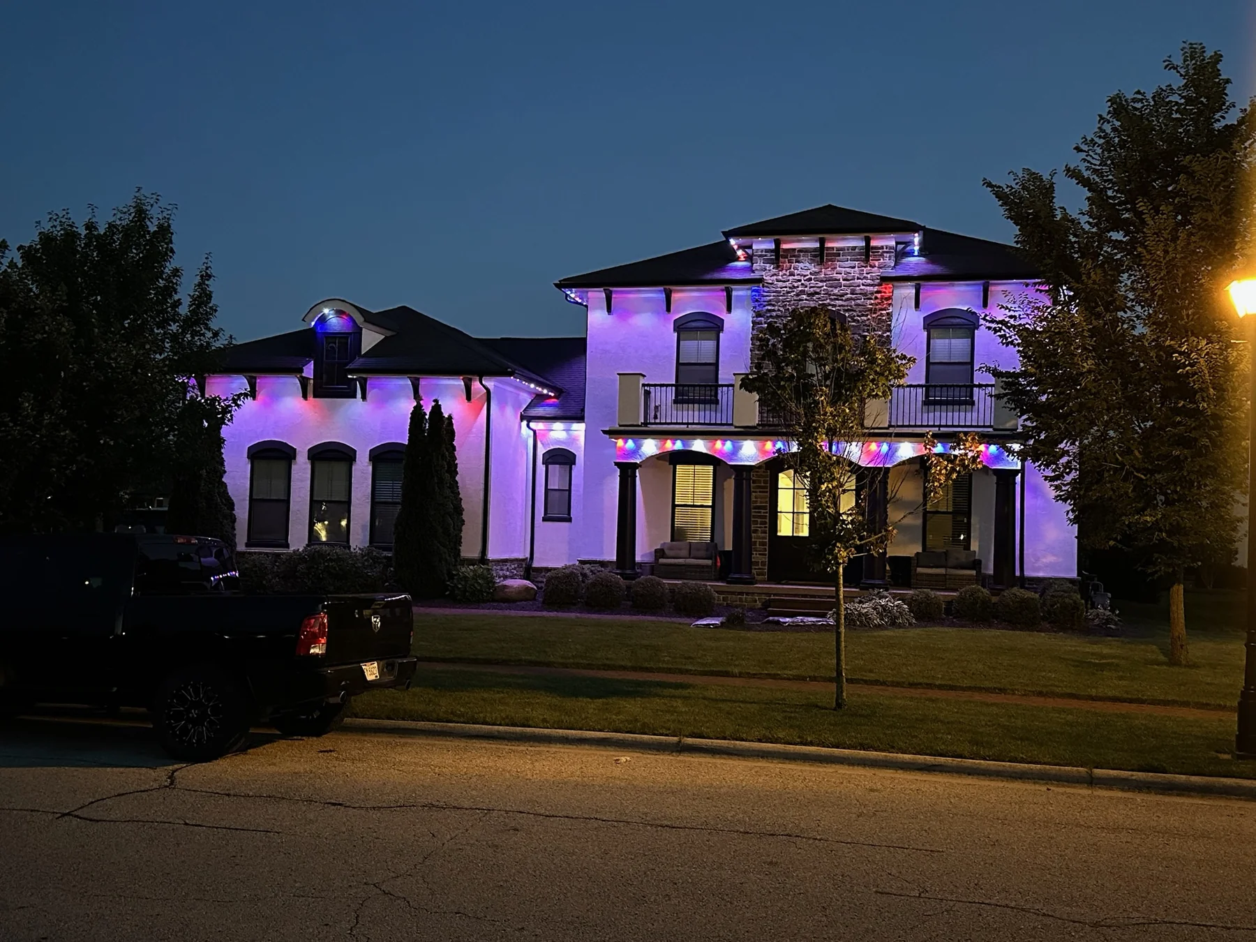 Nighttime photo of a two-story home with purple and red wash showing uneven coverage across the front face