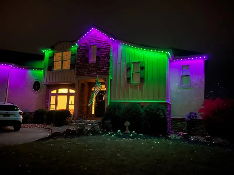 Green and purple permanent Halloween lights on two-story home