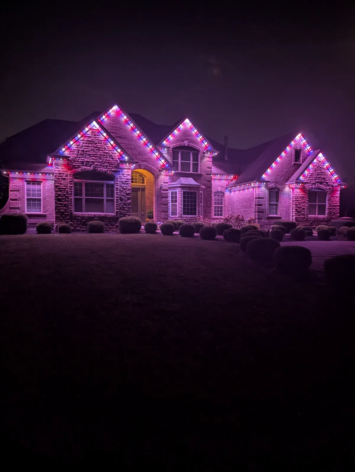 Pink and blue permanent lights on large brick estate at night