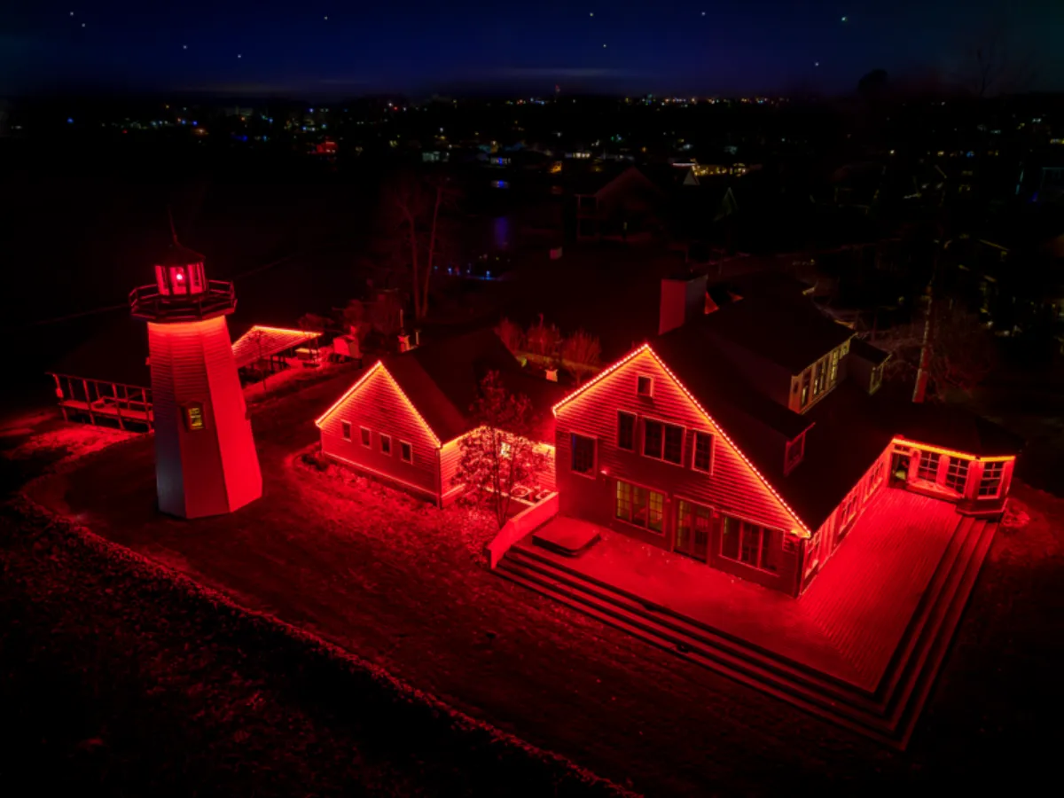 Aerial drone view of home lit in scarlet red permanent lights at night