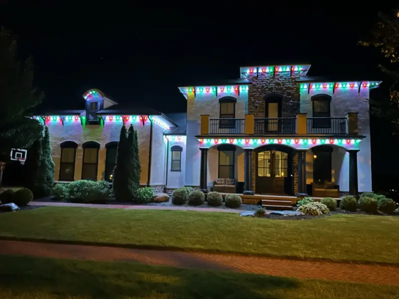 Traditional red and green permanent Christmas lights on stone mansion