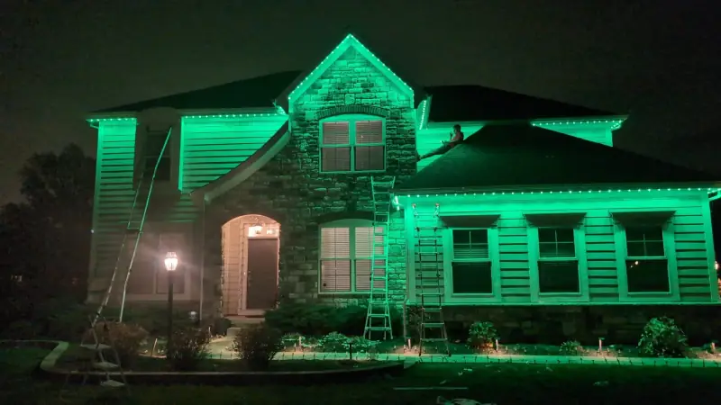 Bright green permanent LED lights illuminating stone home at night