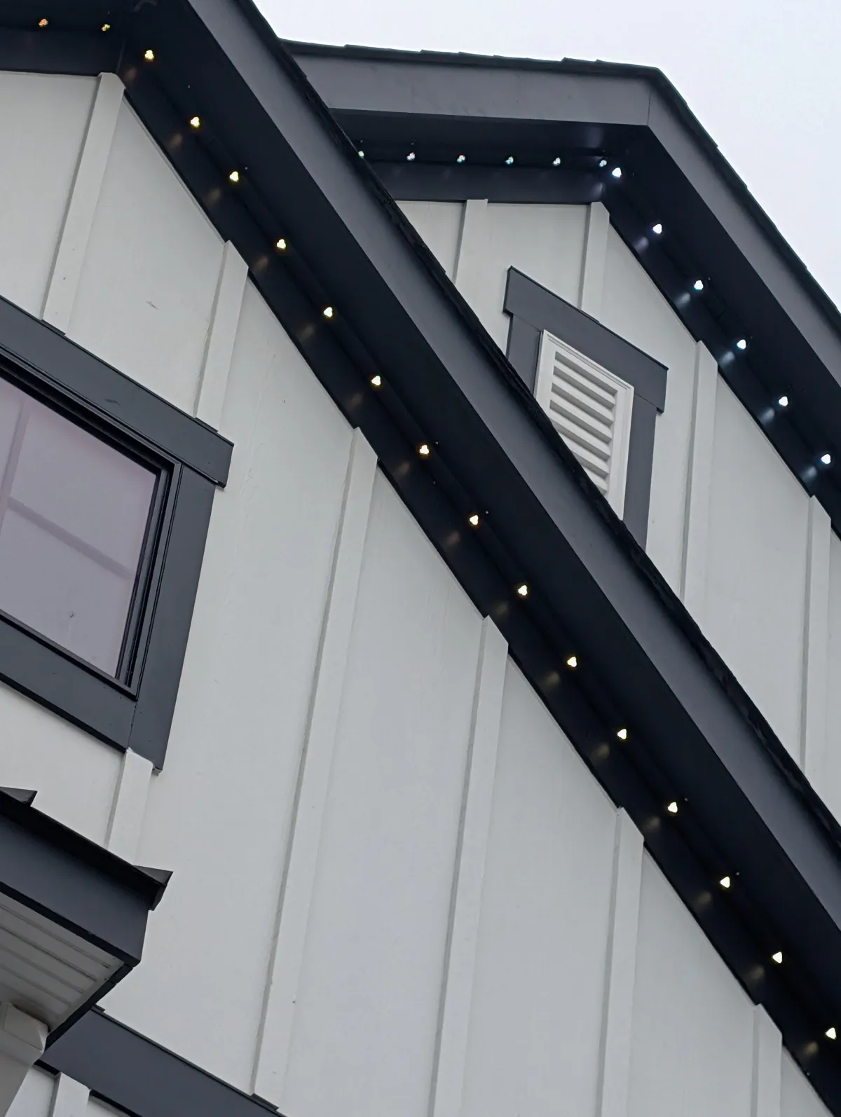 Warm white permanent lights on home during spring evening