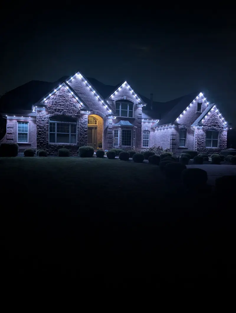 Bright white permanent LED lights outlining brick ranch house roofline