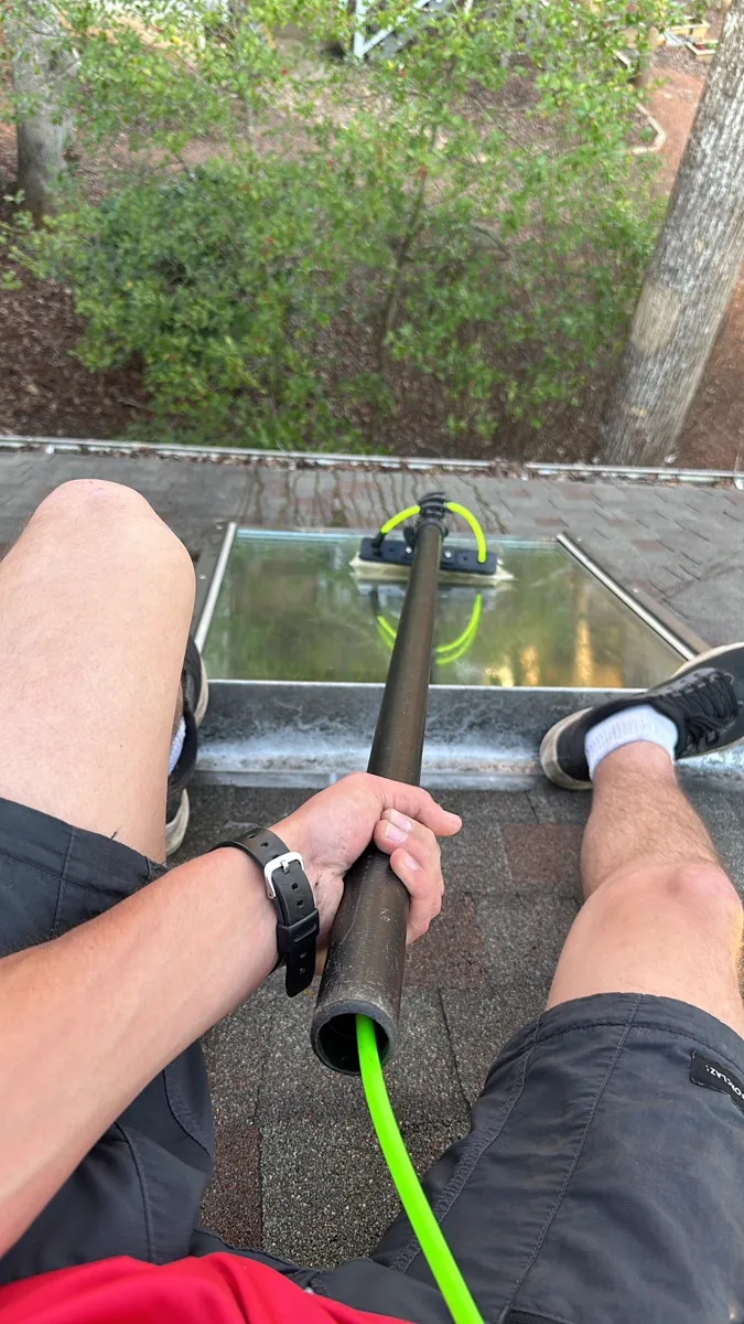 Cleaning skylight window from rooftop with water fed pole